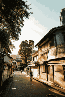 Warm sunlight falls across wooden buildings and the narrow street between them.