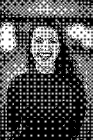 A smiling person with dark hair wears a red top against a softly blurred background. Dithered grayscale treatment.